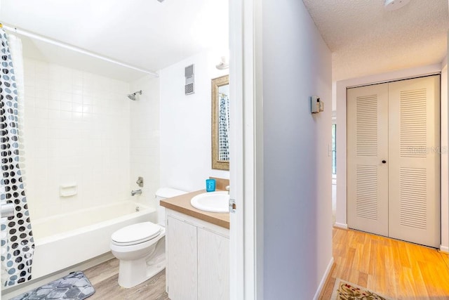 full bathroom featuring shower / bath combo, vanity, hardwood / wood-style flooring, toilet, and a textured ceiling