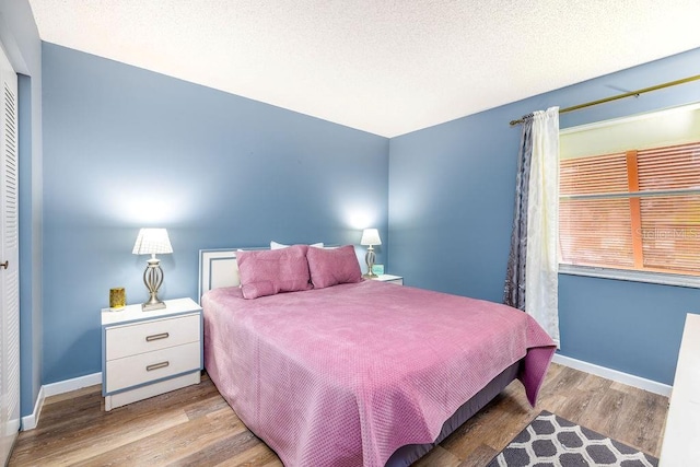 bedroom with wood-type flooring, a textured ceiling, and a closet