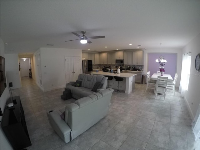 living room featuring light tile floors and ceiling fan with notable chandelier