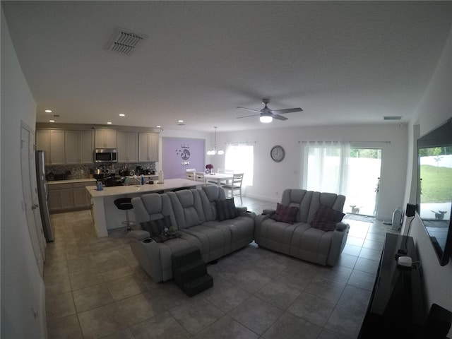 tiled living room with ceiling fan and a wealth of natural light