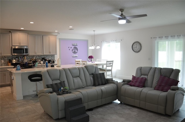 tiled living room featuring ceiling fan with notable chandelier