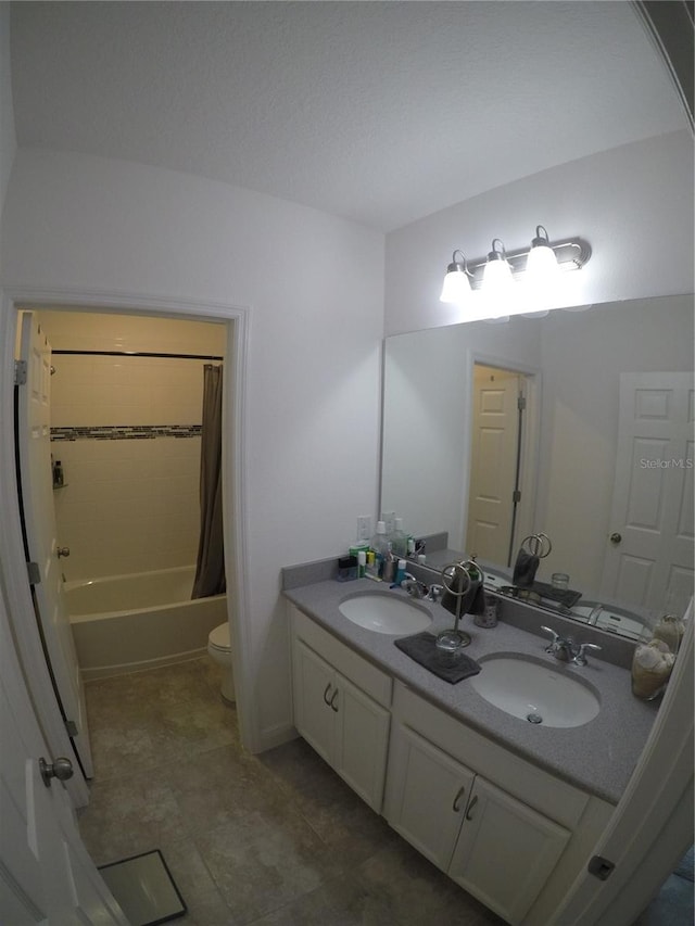 full bathroom featuring toilet, shower / bath combo, double sink, vanity with extensive cabinet space, and tile flooring