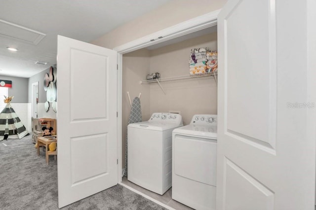 clothes washing area featuring light colored carpet and washer and clothes dryer