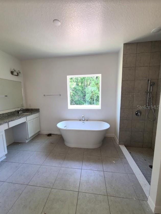 bathroom featuring tile patterned flooring, vanity, shower with separate bathtub, and a textured ceiling