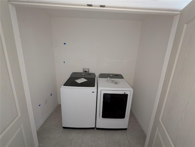 clothes washing area with light tile patterned floors and separate washer and dryer