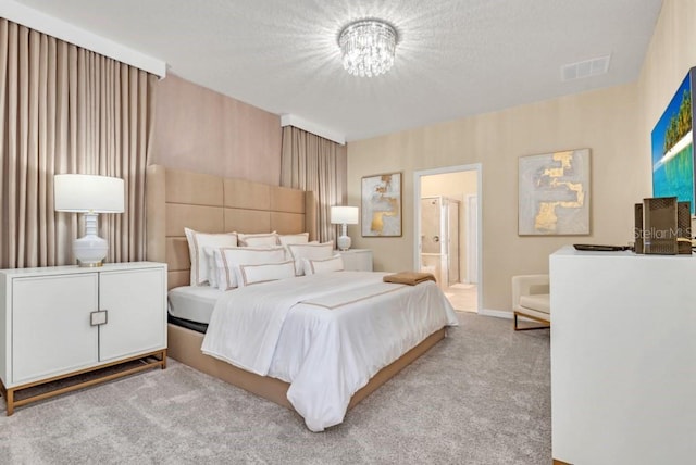 carpeted bedroom featuring an inviting chandelier and ensuite bath