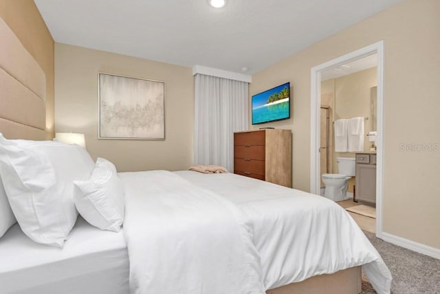 bedroom featuring connected bathroom and light colored carpet