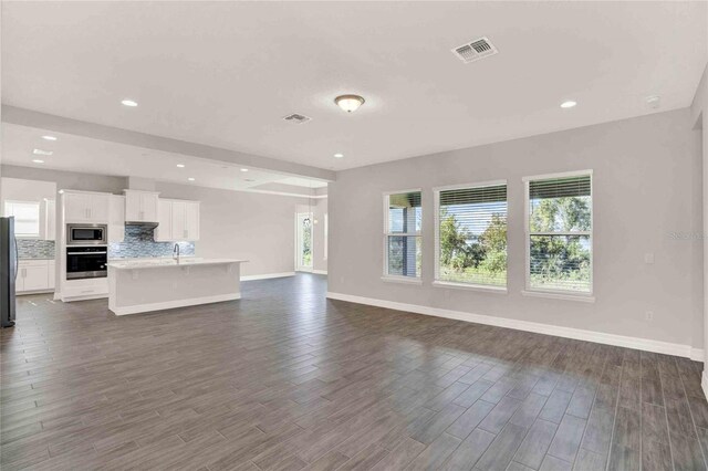 unfurnished living room with a wealth of natural light, dark wood-type flooring, and sink