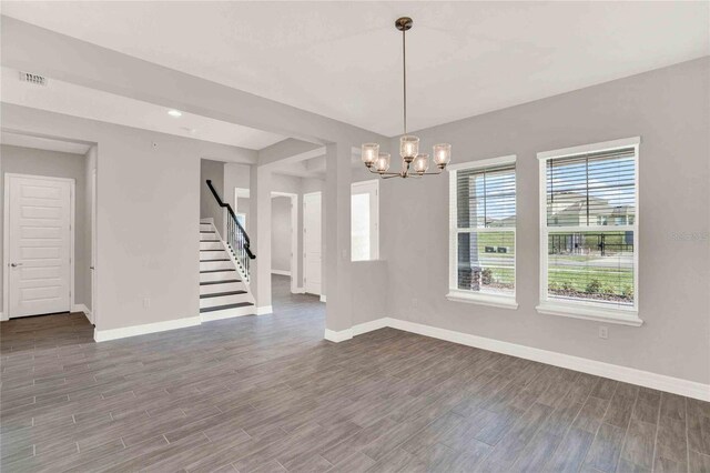 unfurnished dining area featuring an inviting chandelier and hardwood / wood-style flooring