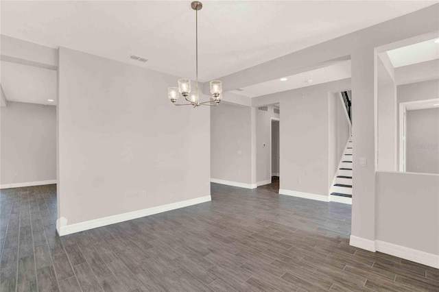 empty room featuring dark hardwood / wood-style flooring and an inviting chandelier