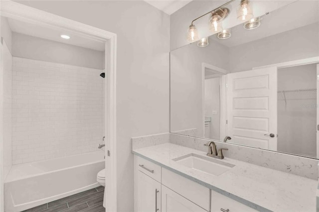 full bathroom with vanity, tiled shower / bath combo, and toilet