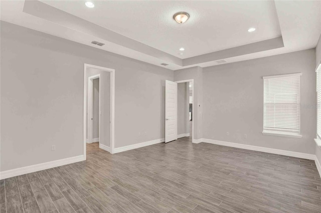 unfurnished room with wood-type flooring and a tray ceiling