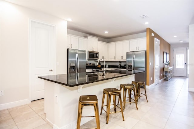 kitchen featuring white cabinets, an island with sink, and stainless steel appliances