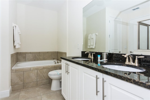 bathroom with toilet, large vanity, dual sinks, tile floors, and tiled tub