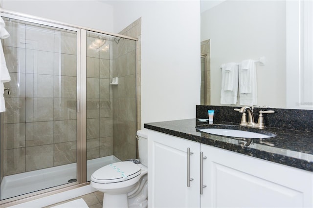 bathroom featuring toilet, a shower with door, tile floors, and oversized vanity