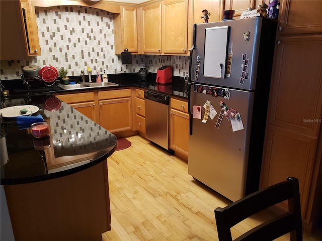 kitchen with sink, stainless steel appliances, light wood-type flooring, and backsplash