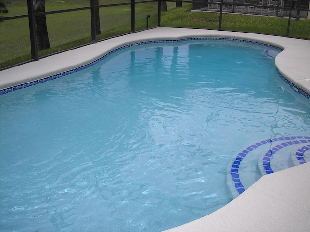 view of pool featuring a yard and glass enclosure