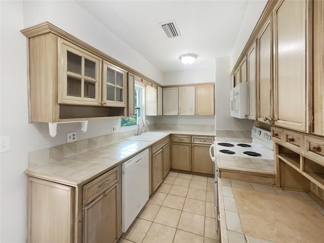 kitchen featuring tile counters, light tile patterned floors, white appliances, and sink