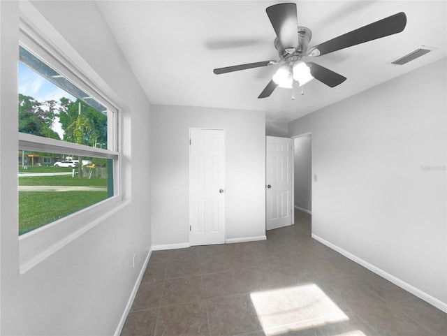 unfurnished bedroom featuring dark tile patterned flooring and ceiling fan