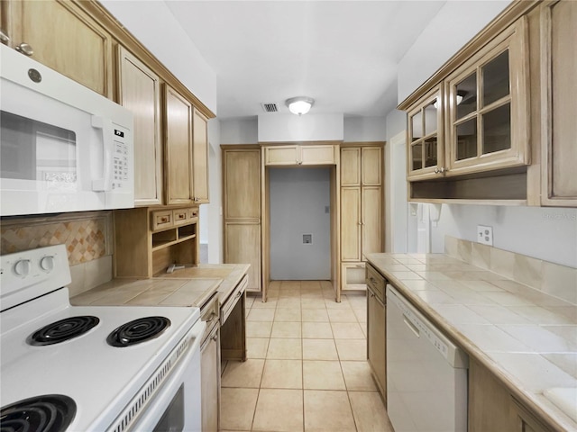 kitchen with tile counters, white appliances, and light tile patterned floors