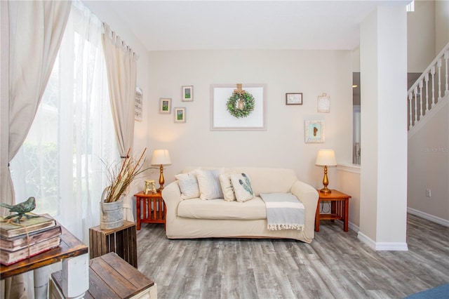 living area with light wood-type flooring, baseboards, and stairs