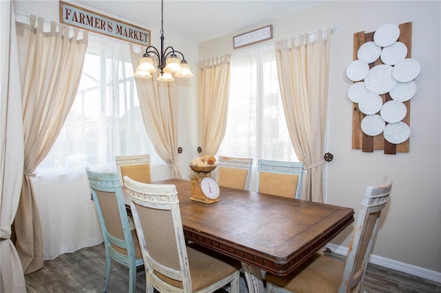 dining room featuring dark wood-type flooring, a chandelier, a healthy amount of sunlight, and baseboards