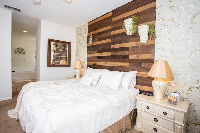 bedroom with light carpet, wallpapered walls, visible vents, ensuite bath, and wood walls