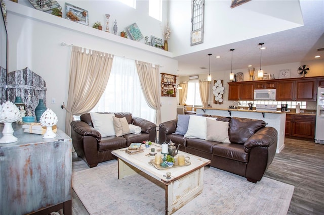 living room featuring light wood-style floors, recessed lighting, and a high ceiling