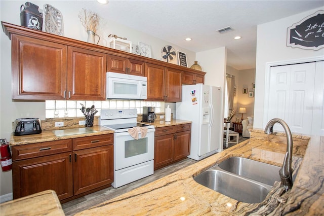 kitchen featuring light stone counters, recessed lighting, visible vents, a sink, and white appliances