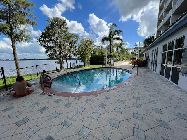 view of swimming pool featuring a water view and a patio