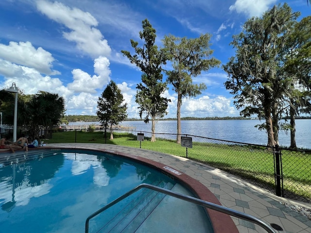 view of pool featuring a water view and a yard