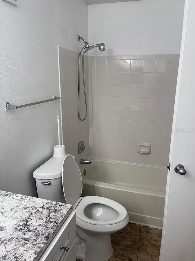 full bathroom featuring tiled shower / bath, toilet, tile floors, and vanity