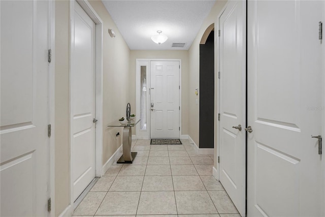 hall featuring a textured ceiling and light tile flooring