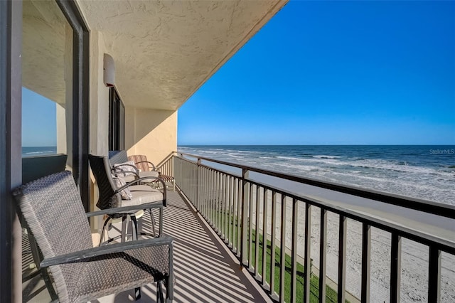 balcony featuring a water view and a beach view