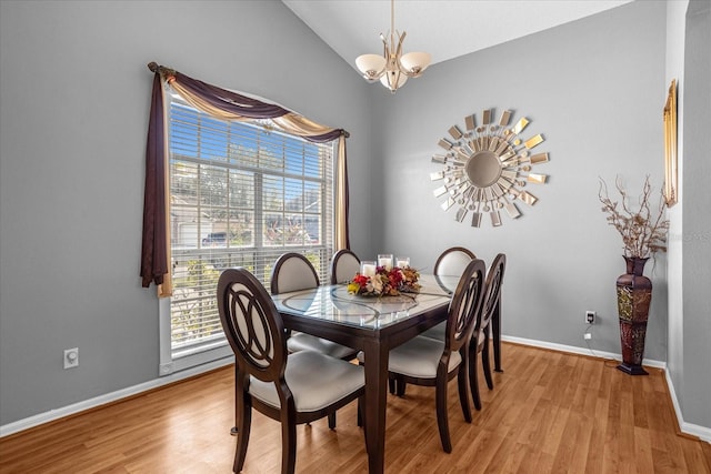 dining area with lofted ceiling, a notable chandelier, and light wood-type flooring