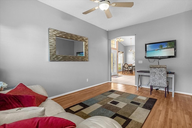 living room with light hardwood / wood-style floors and ceiling fan with notable chandelier