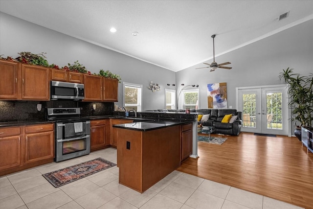 kitchen featuring ceiling fan, high vaulted ceiling, light hardwood / wood-style floors, dark stone counters, and stove