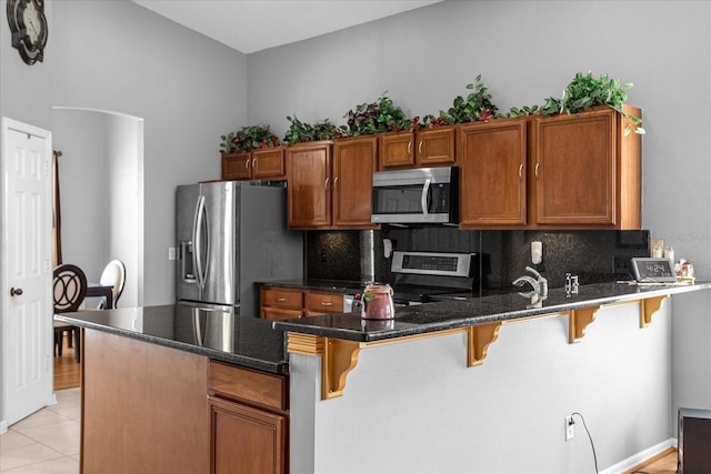 kitchen with light tile floors, a breakfast bar, tasteful backsplash, and stainless steel appliances