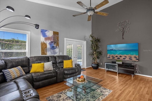 living room with plenty of natural light, light hardwood / wood-style floors, ceiling fan, and french doors