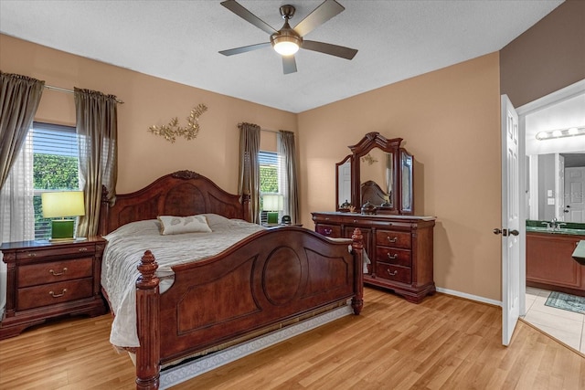 tiled bedroom featuring multiple windows, ensuite bath, ceiling fan, and a textured ceiling