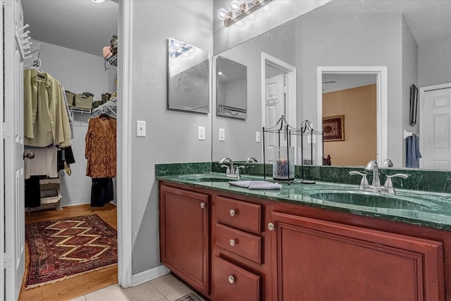 bathroom featuring a textured ceiling, tile floors, double sink, and large vanity