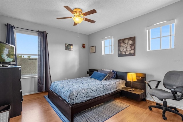 bedroom featuring light hardwood / wood-style floors, a textured ceiling, and ceiling fan