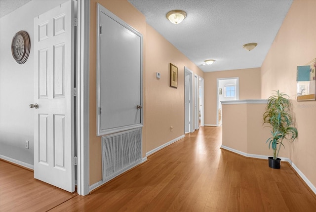 corridor with light hardwood / wood-style floors and a textured ceiling