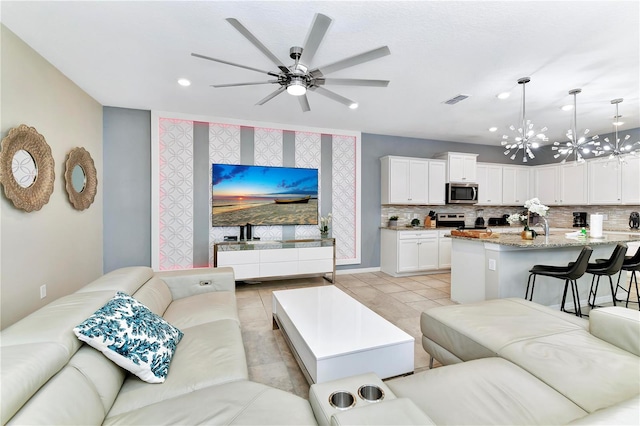 living room featuring ceiling fan with notable chandelier and light tile flooring