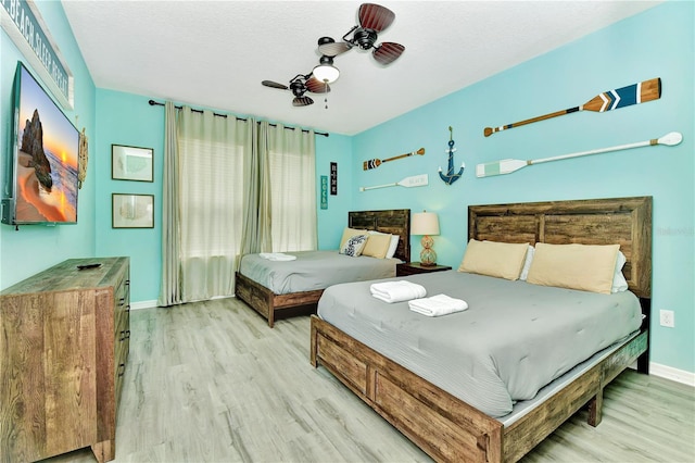 bedroom with a textured ceiling, ceiling fan, and light hardwood / wood-style flooring