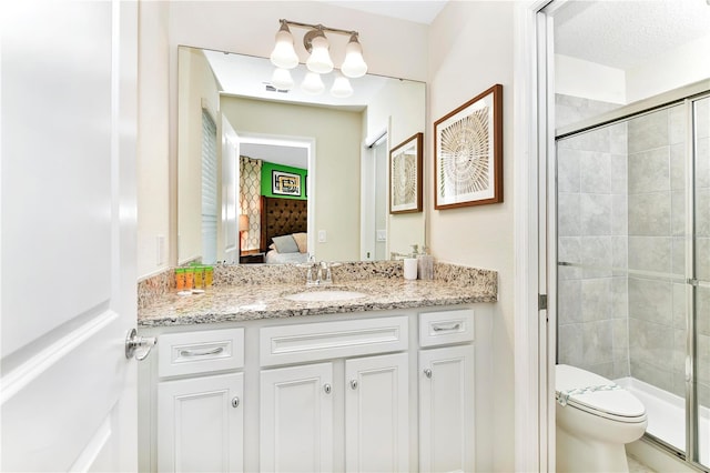 bathroom with oversized vanity, toilet, a textured ceiling, and a shower with shower door