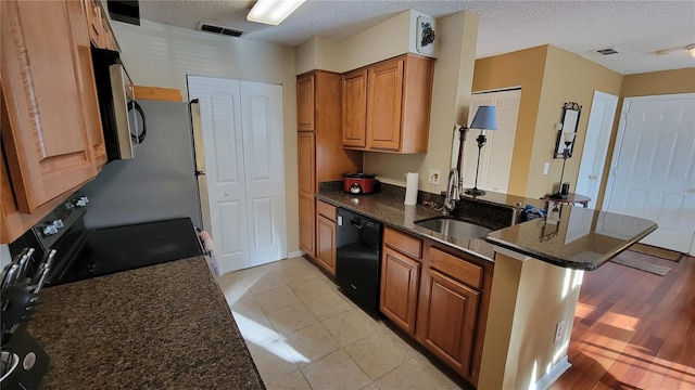 kitchen with kitchen peninsula, dark stone counters, black dishwasher, range, and a textured ceiling