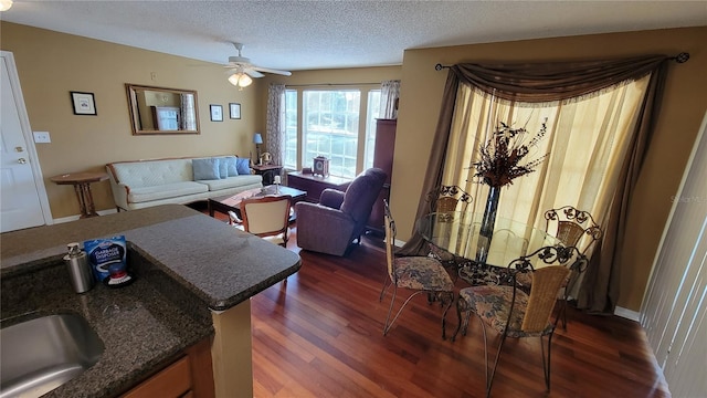 interior space featuring a textured ceiling, ceiling fan, dark stone countertops, and dark hardwood / wood-style flooring