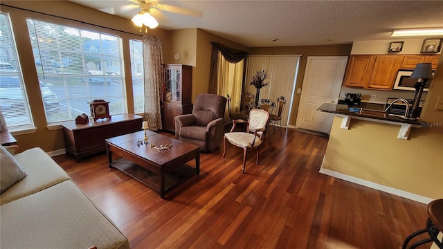 living room with dark hardwood / wood-style flooring, a textured ceiling, and ceiling fan