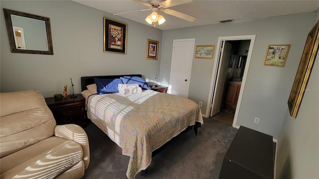 bedroom featuring ensuite bath, a textured ceiling, ceiling fan, and dark colored carpet